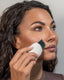 The model wearing Woman using ultrasonic scrubber spatula on her skin on a neutral background
